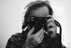Grayscale image of a tattooed photographer holding a camera close-up. jigsaw puzzle