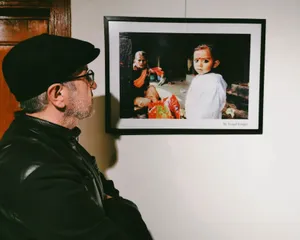 A man in a gallery viewing a framed portrait of two people, evoking curiosity. jigsaw puzzle