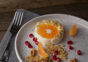 A gourmet dessert featuring orange slices, walnuts, and pomegranate seeds on a white plate. jigsaw puzzle