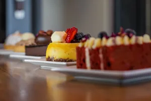 Close-up of assorted gourmet desserts on plates, featuring cheesecake, chocolate cake, and red velvet. jigsaw puzzle