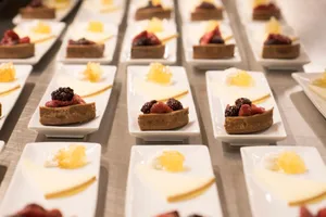 Elegant presentation of berry pastries and cheese served on white platters in a restaurant setting. jigsaw puzzle