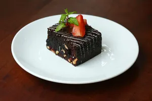 Rich chocolate brownie topped with strawberries and mint on a white plate. jigsaw puzzle