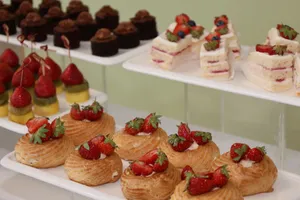 Close-up of assorted pastries and desserts displayed on white trays, featuring strawberries and chocolate. jigsaw puzzle