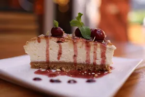 Close-up of a creamy cheesecake slice with cherry topping and mint garnish. jigsaw puzzle