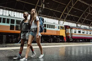 Two women with backpacks walking and smiling at a railway station. jigsaw puzzle