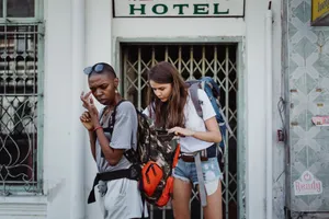 Two young female backpackers checking their belongings outside a hotel entrance. jigsaw puzzle