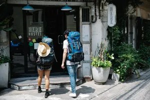 Back view of anonymous couple of tourists with rucksacks walking on street and entering hostel door during trip jigsaw puzzle
