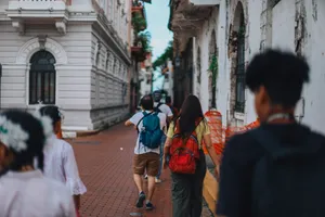 A group of people walking down a paved alley with backpacks, showcasing city life. jigsaw puzzle