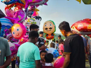 Vibrant outdoor festival with balloons and diverse crowd, showcasing joyful atmosphere. jigsaw puzzle
