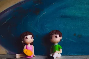 Small plastic figures of man with girlfriend sitting against canvas with artwork of blue ocean jigsaw puzzle