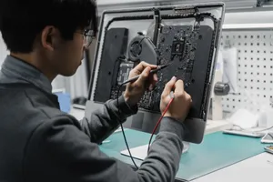 A technician works on a computer motherboard using tools at a workspace, focusing on electronics repair. jigsaw puzzle