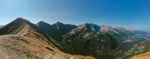 Stunning panoramic shot of a vast mountain range with clear blue skies, showcasing untouched natural beauty. jigsaw puzzle