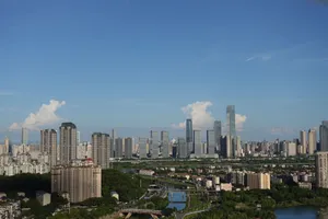 A stunning aerial view of a modern city skyline under a clear blue sky with scattered clouds. jigsaw puzzle