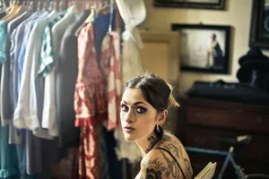 Woman with tattoos sitting in a room filled with stylish clothing and accessories. jigsaw puzzle