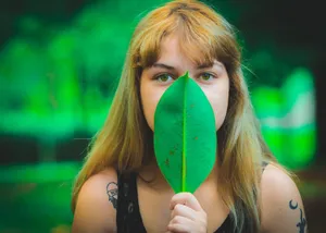 A young woman in a summer portrait holding a green leaf in a lush forest setting. jigsaw puzzle