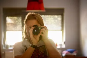 A woman capturing a self-portrait indoors with a camera, showcasing a cozy and artistic atmosphere. jigsaw puzzle