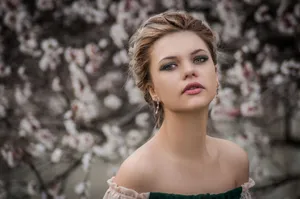 Portrait of an elegant woman with charming makeup, posing in front of blossoming trees symbolizing spring beauty. jigsaw puzzle