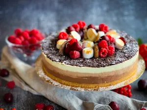 Delicious triple-layer cheesecake topped with fresh berries and chocolate shavings, ideal for celebrations. jigsaw puzzle