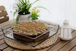 A beautifully decorated homemade chocolate cake topped with pistachios in a cozy setting. jigsaw puzzle