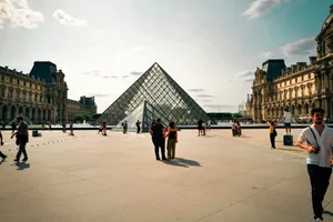 A daytime view of the Louvre Pyramid in Paris with people walking around. jigsaw puzzle
