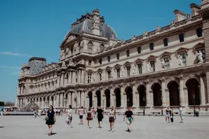 Tourists walking outside the iconic Louvre Museum in Paris under a clear blue sky. jigsaw puzzle
