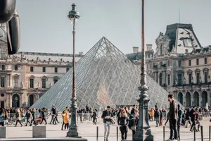 People gather in front of the iconic Louvre Pyramid in Paris during a sunny day, enjoying sightseeing. jigsaw puzzle