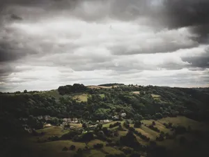 A scenic aerial view of a rural countryside with dark clouds and lush greenery. jigsaw puzzle