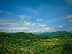 Expansive view of green hills and mountains beneath a clear blue sky, perfect for nature enthusiasts. jigsaw puzzle