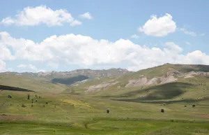 Expansive countryside with rolling hills and clouds under a clear summer sky. jigsaw puzzle
