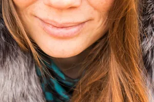 Close-up of a woman's smile, showcasing natural red hair and warm winter clothing. jigsaw puzzle