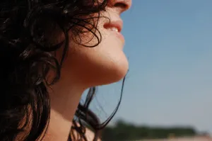 Close-up profile of a woman with curly hair enjoying a sunny day outdoors. jigsaw puzzle