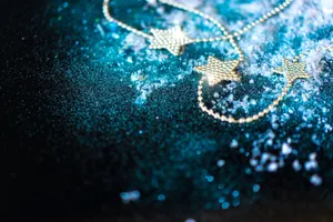 Golden star garland on a shimmering blue surface with scattered snowflakes, creating a festive mood. jigsaw puzzle