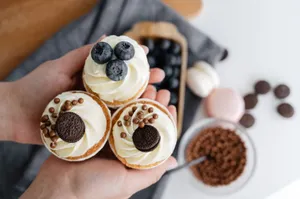Top view of crop anonymous person showing delicious cupcakes with blueberries and chocolate sweets against blurred background of various dessert jigsaw puzzle