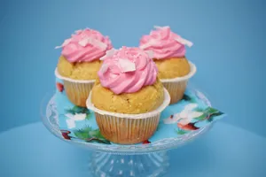 Three homemade cupcakes with pink frosting on a glass stand, perfect for dessert and parties. jigsaw puzzle