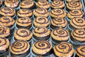 A tray of delectable chocolate cupcakes with icing swirls and crunchy toppings, perfect for a sweet treat. jigsaw puzzle