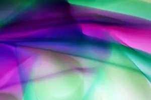 A dynamic and colorful abstract design with a blend of purple and green gradients creating a fluid wave pattern. jigsaw puzzle