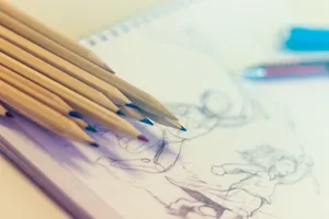 Close-up of colored pencils on sketch-filled notepad, perfect for creativity concepts. jigsaw puzzle