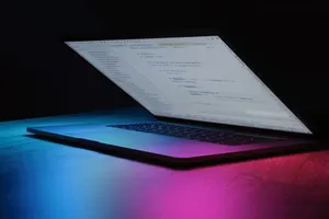 A partially open laptop displaying code, bathed in vibrant neon lighting. jigsaw puzzle
