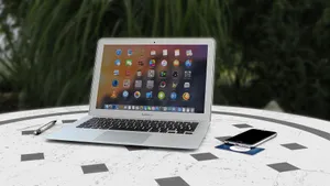 Open laptop with app icons displayed, smartphone and pen on white table outdoors. jigsaw puzzle