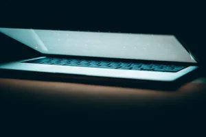 A close-up of a partially open laptop on a wooden surface, displayed in a moody lighting. jigsaw puzzle