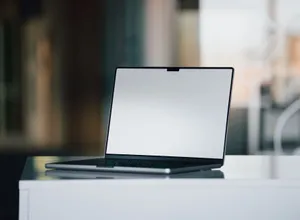 A sleek laptop with a blank screen sits on a white desk in a contemporary office setting. jigsaw puzzle