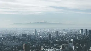 Panoramic view of Tokyo cityscape with Mount Fuji looming in the background, under cloudy skies. jigsaw puzzle