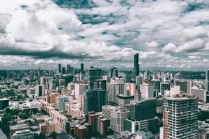 Dynamic cityscape featuring towering skyscrapers and a vibrant urban skyline under a cloudy sky. jigsaw puzzle