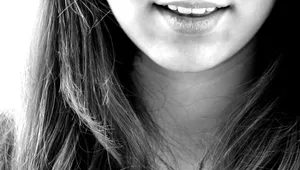 Black and white close-up of a smiling woman's mouth and chin with long hair. jigsaw puzzle