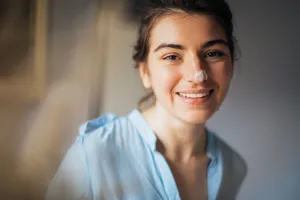 Portrait of a smiling woman with cream on her nose, softly lit indoors. jigsaw puzzle