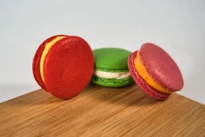 Vibrant French macarons in red, green, and pink displayed on a wooden board. jigsaw puzzle