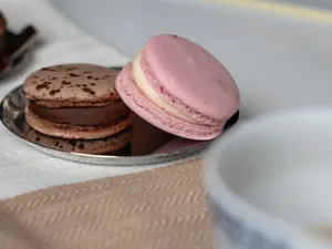Artistic close-up of pink and chocolate macarons on a reflective plate, showcasing fine French pastry. jigsaw puzzle