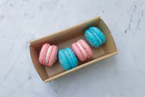 Top view of pink and blue macarons in a cardboard box on a marble surface. jigsaw puzzle