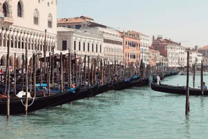 Iconic gondolas lined up along Venice's Grand Canal under a clear sky. jigsaw puzzle