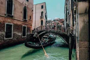 Gondola gliding under a picturesque bridge in Venice, capturing essence of urban Venetian waterways. jigsaw puzzle